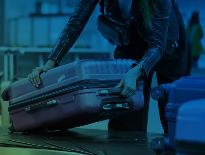 Traveler picking up suitcase off baggage claim carousel